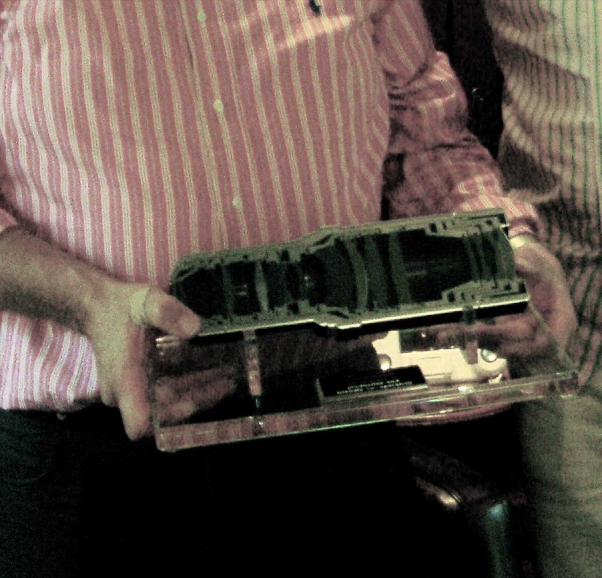A precision lens element from an ASML lithography system, held by a technician for inspection.