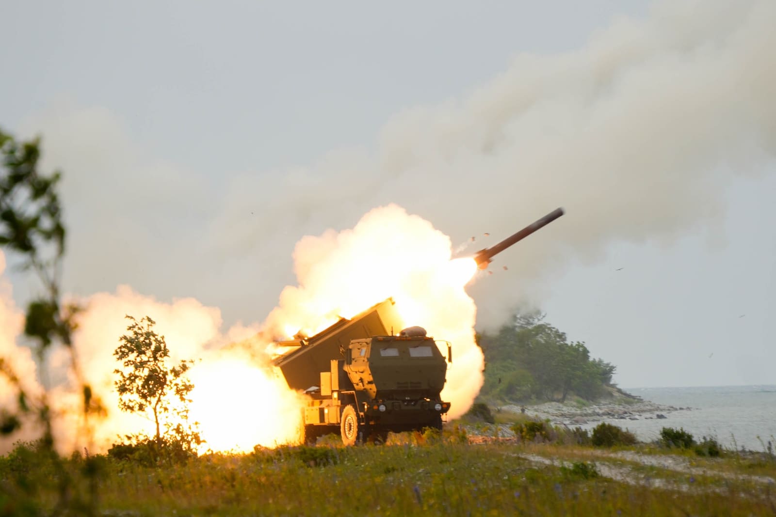 An M142 HIMARS launcher firing a training rocket during a live-fire exercise on the Estonian coast