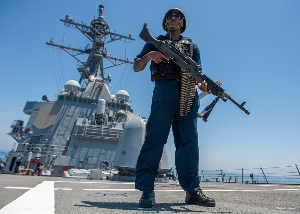 A sailor stands watch with a machine gun aboard the guided-missile destroyer USS Paul Hamilton while transiting the Strait of Hormuz