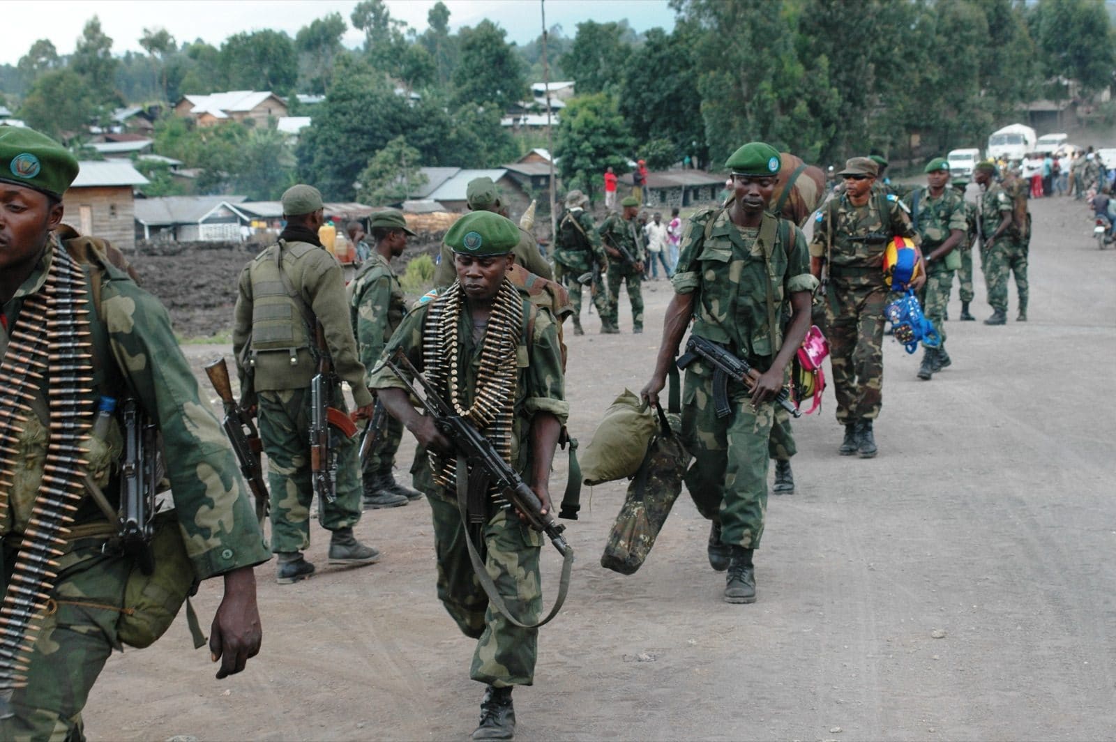 FARDC soldiers in green fatigues holding rifles reinforce a position on a hillside outside Goma, hills in the background