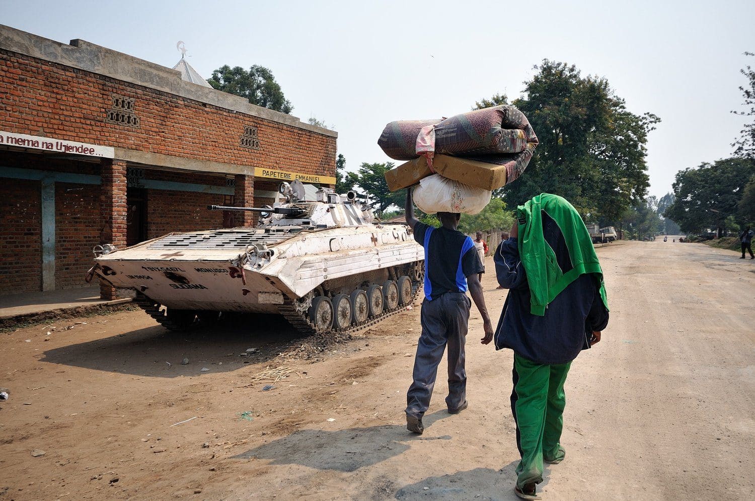 Congolese civilians carrying belongings on their heads walk along a dirt road fleeing fighting in Rutshuru territory, North Kivu
