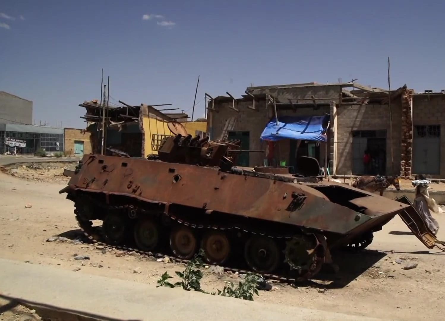 Civilians walking past a destroyed armored vehicle on a street in Axum, Tigray, June 2021