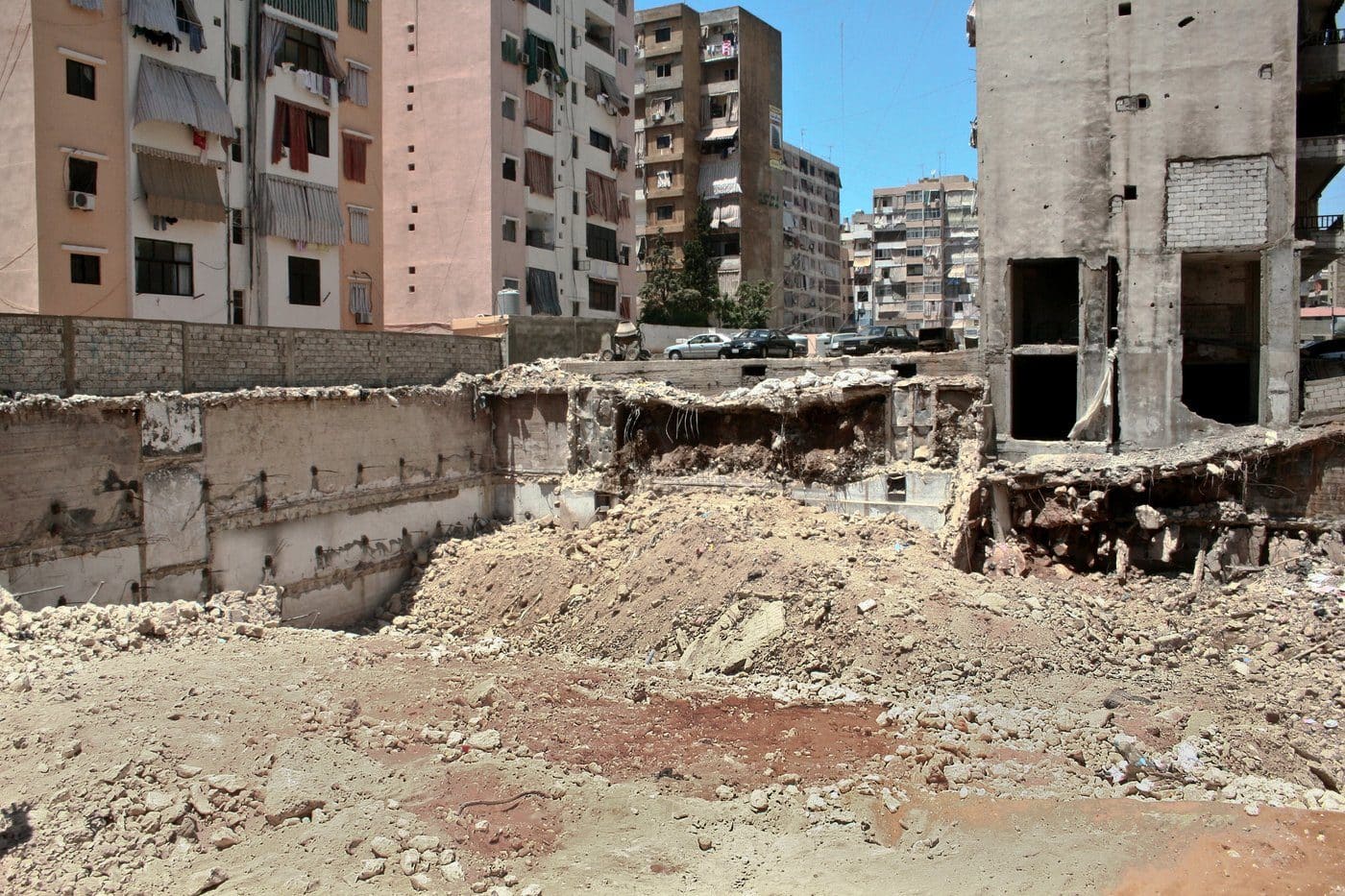 A bombed-out building and crater amid apartment towers in Beirut's southern Dahieh district