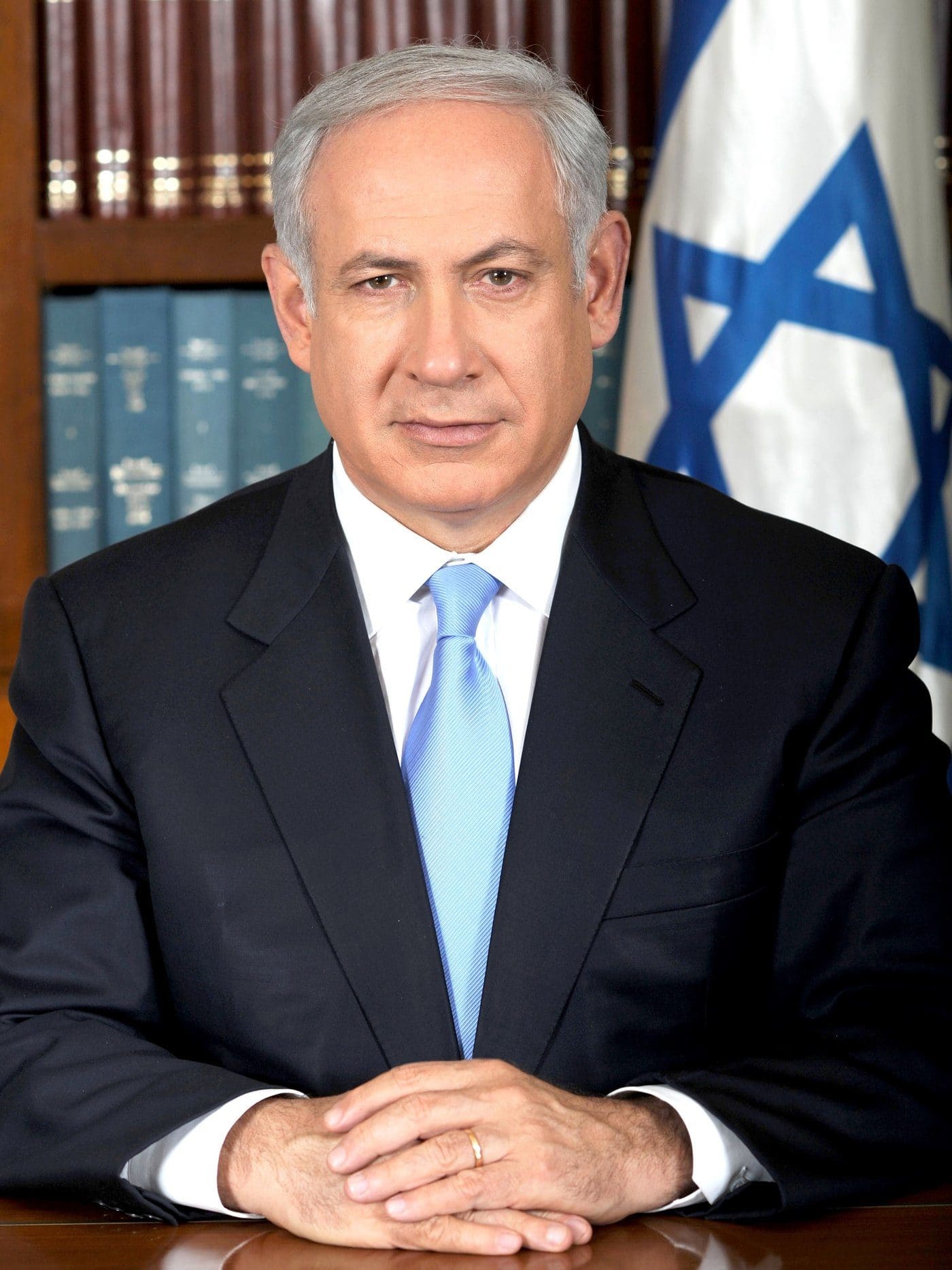 Official portrait of Israeli Prime Minister Benjamin Netanyahu seated at a desk with an Israeli flag behind him