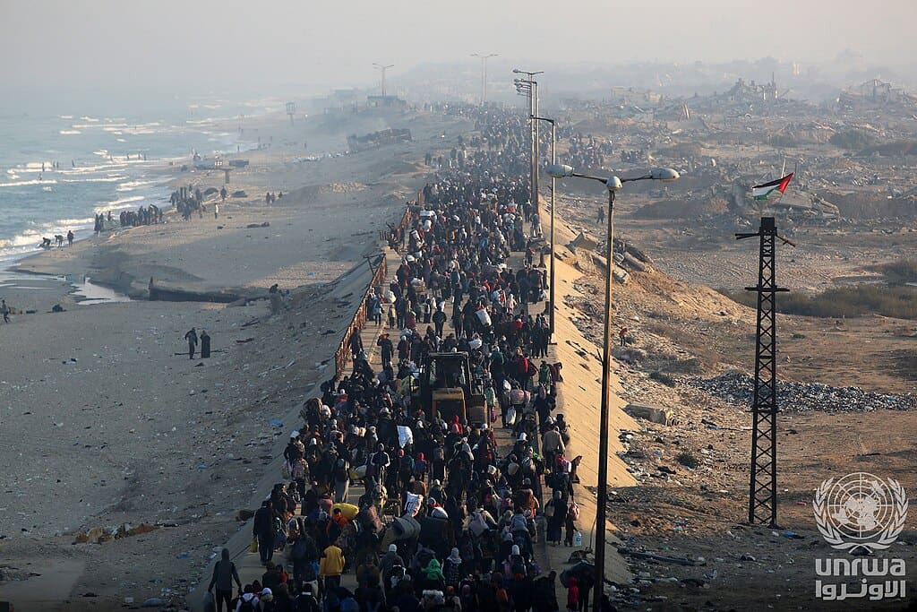 Displaced Palestinians walk with belongings along Al-Rasheed Street as they return toward northern Gaza