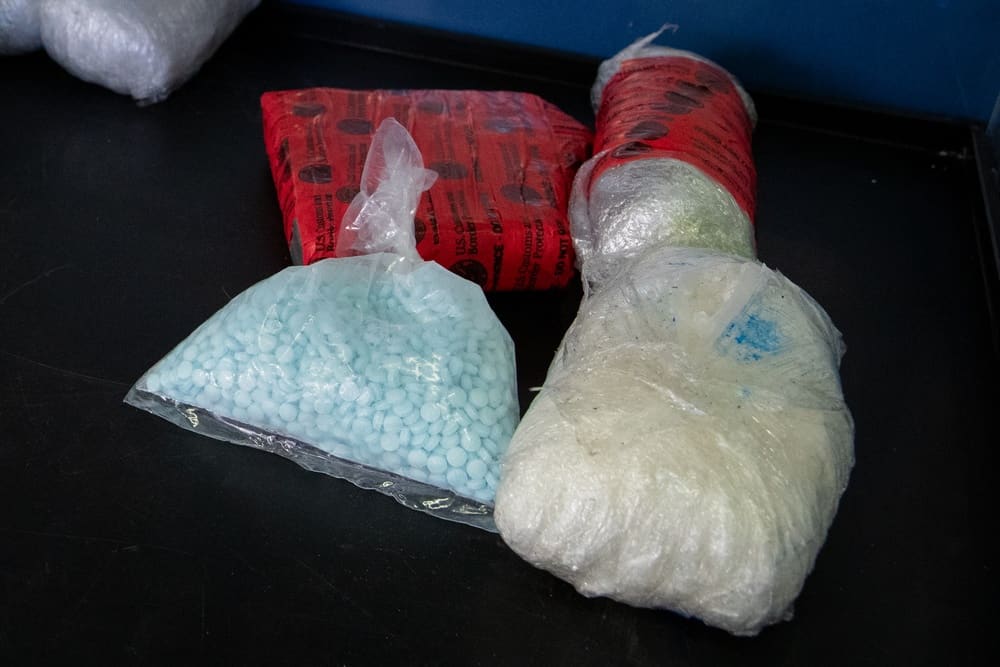 Seized fentanyl pills, fentanyl powder, black tar heroin, and methamphetamine laid out after a Nogales border seizure