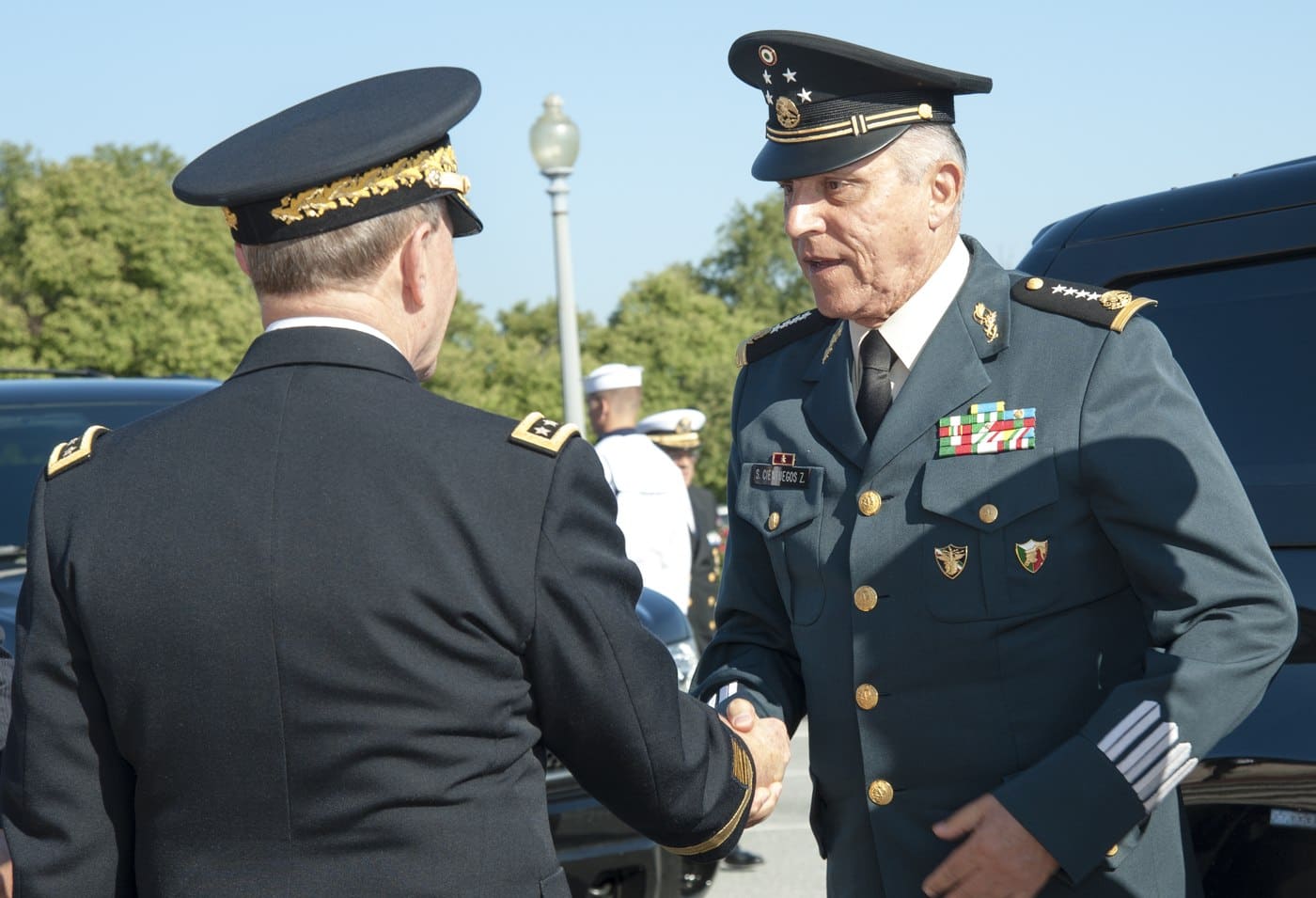 Mexican Secretary of National Defense General Salvador Cienfuegos Zepeda, nametag visible, shaking hands with a US officer in Washington, D.C.