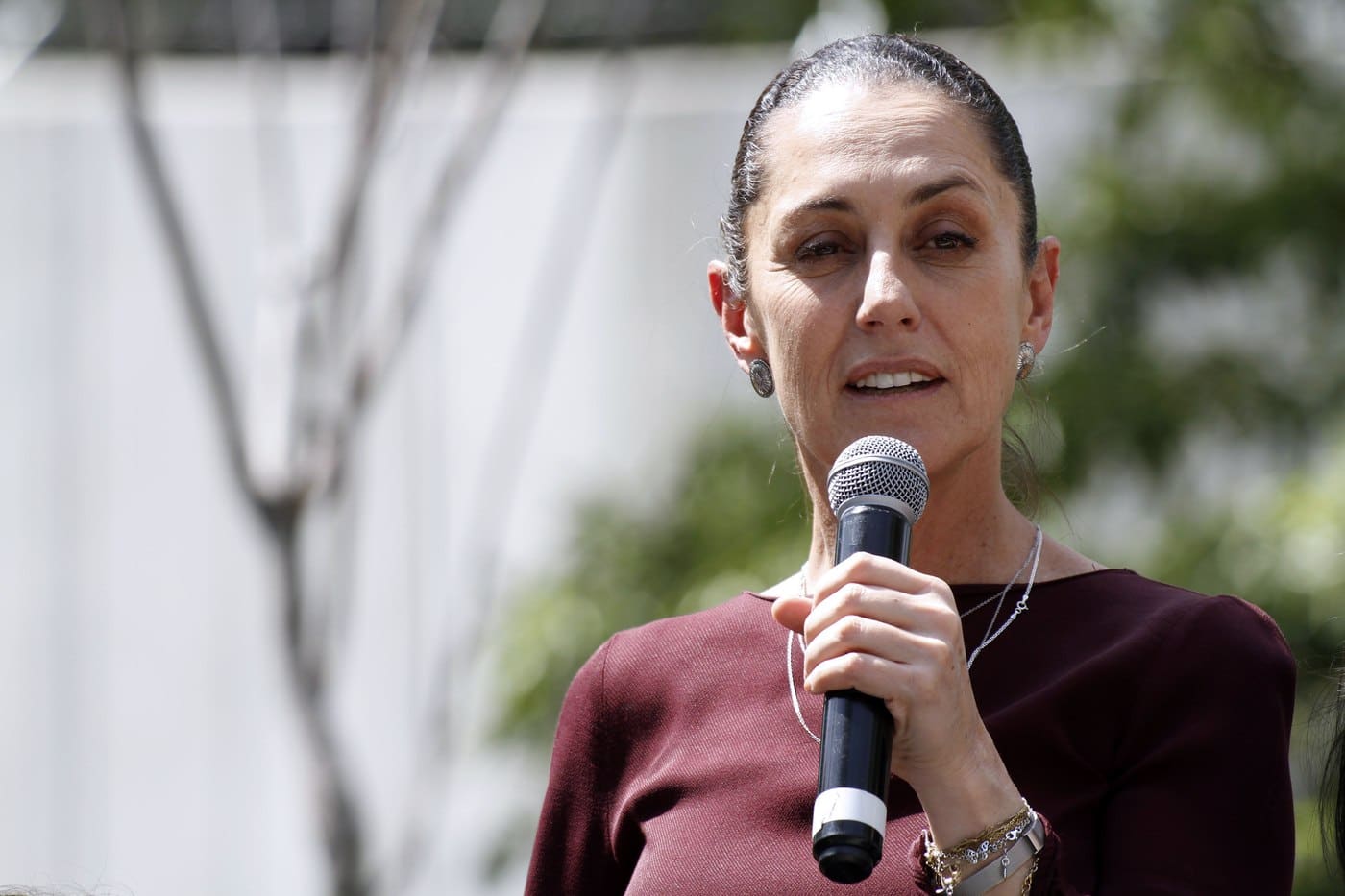 Claudia Sheinbaum speaking into a microphone at a public event in Mexico City
