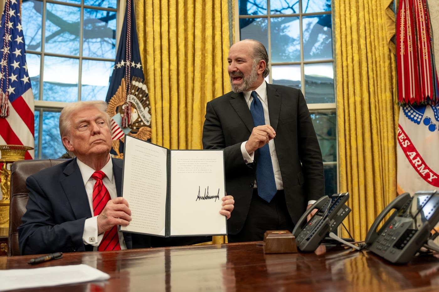 President Donald Trump signing executive orders at his desk in the Oval Office in early 2025