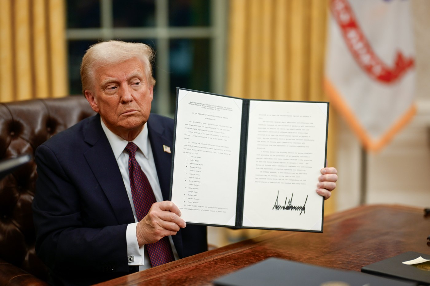 President Donald Trump holding up a signed proclamation in the Oval Office on his first day back in office, January 20, 2025