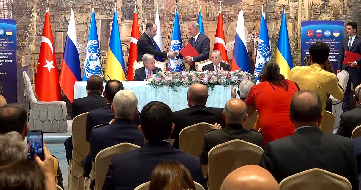Turkish and Russian defense ministers shake hands at the Black Sea Grain Initiative signing ceremony in Istanbul, with UN Secretary-General Guterres and Turkish President Erdogan seated at the table