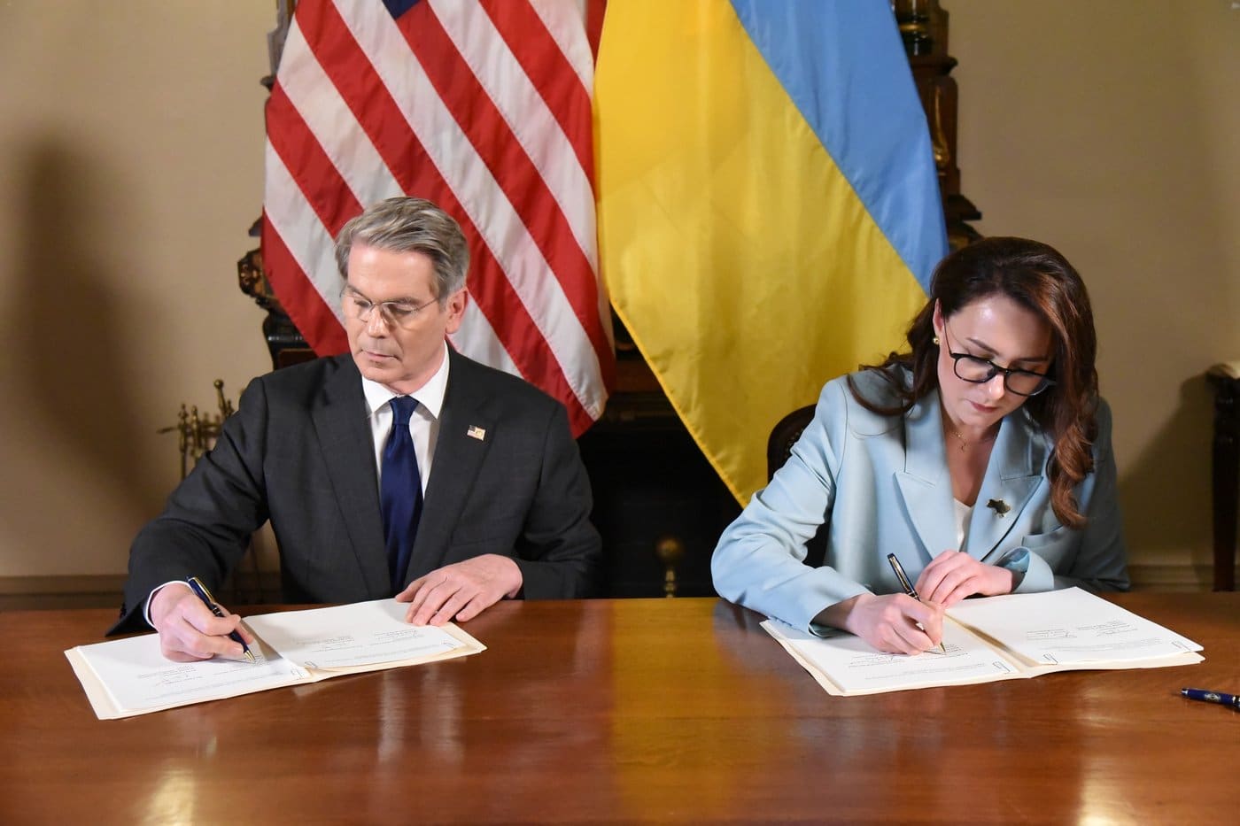 U.S. Treasury Secretary Scott Bessent and Ukrainian First Deputy Prime Minister Yulia Svyrydenko sign the US-Ukraine minerals agreement at a table with both countries' flags behind them
