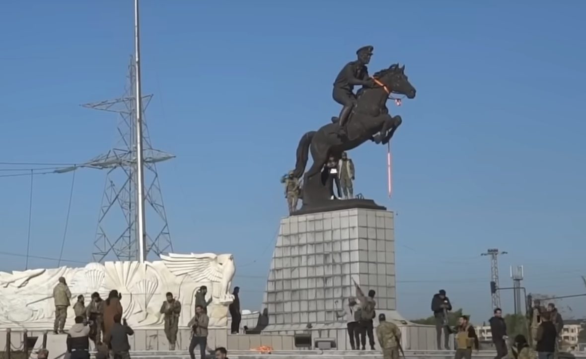 Syrian opposition fighters gathered around an equestrian statue in western Aleppo on the day the city fell
