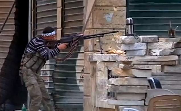 A Free Syrian Army fighter firing a machine gun during street combat in Aleppo