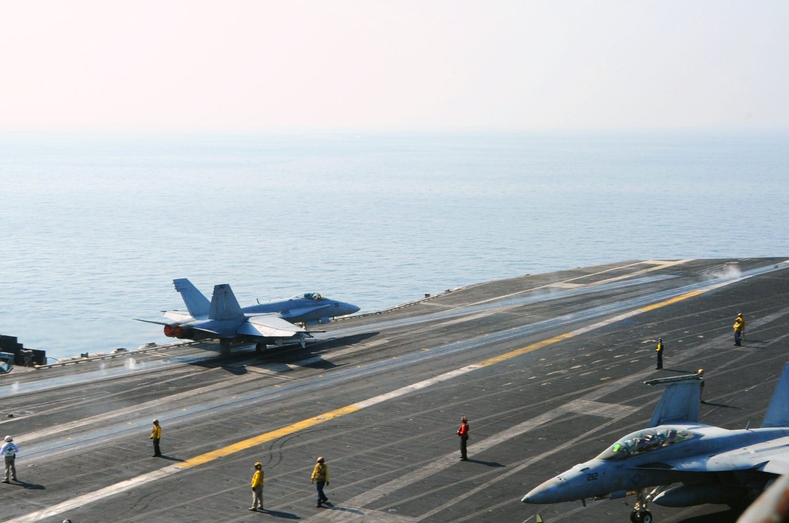 An F/A-18C Hornet fighter jet launching from the flight deck of a US Navy aircraft carrier
